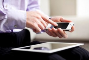 Businessman using and iPhone next to an iPad.