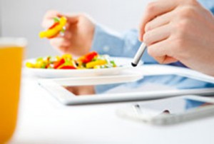 Picture of a man using a tablet while eating.